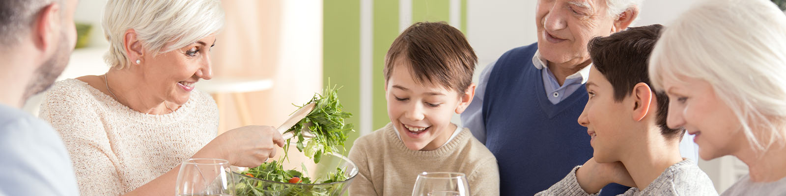 A senior couple eating dinner at the table surrounded by family