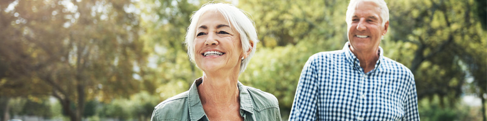 Senior couple smiling and walking through the grass