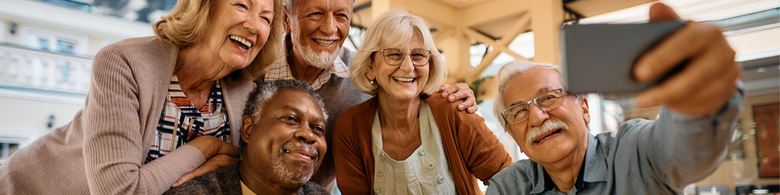 A group of senior living residents huddled together as they smile for a selfie picture