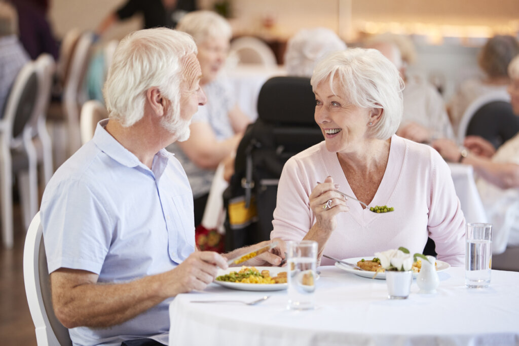 A male senior living resident sitting at a dinner table with a female senior living resident