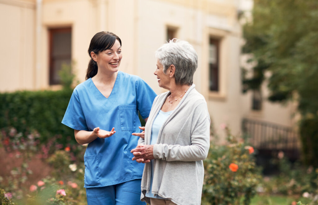 A senior living employee walking with a female resident outdoors